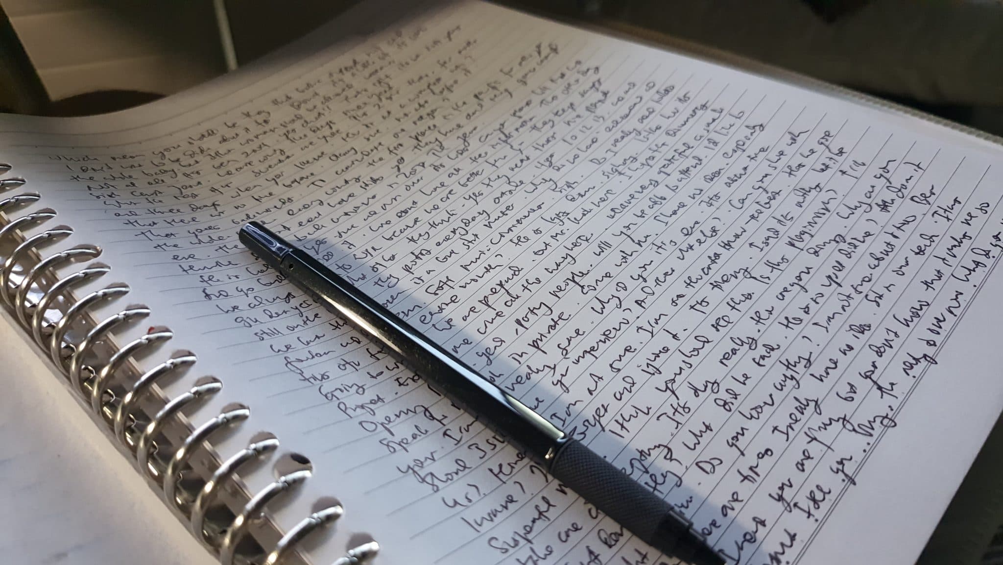 An open notebook with handwritten notes and a pen