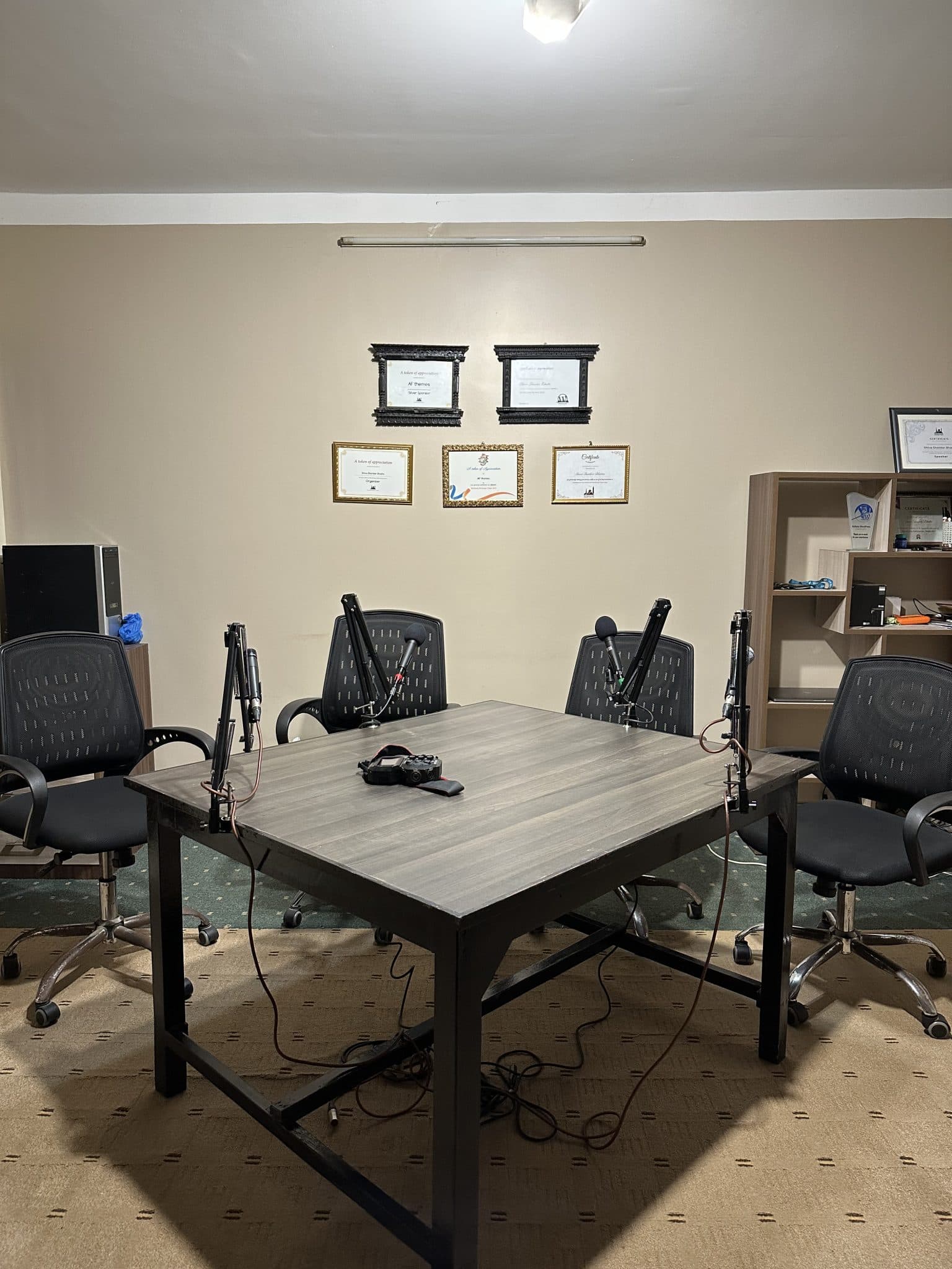A podcast set with four chairs and four microphones around a table